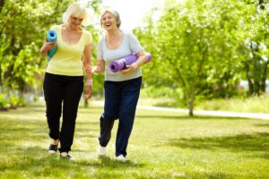 Senior Women Carrying Yoga Mats Talk as They Walk_Socialization for Seniors