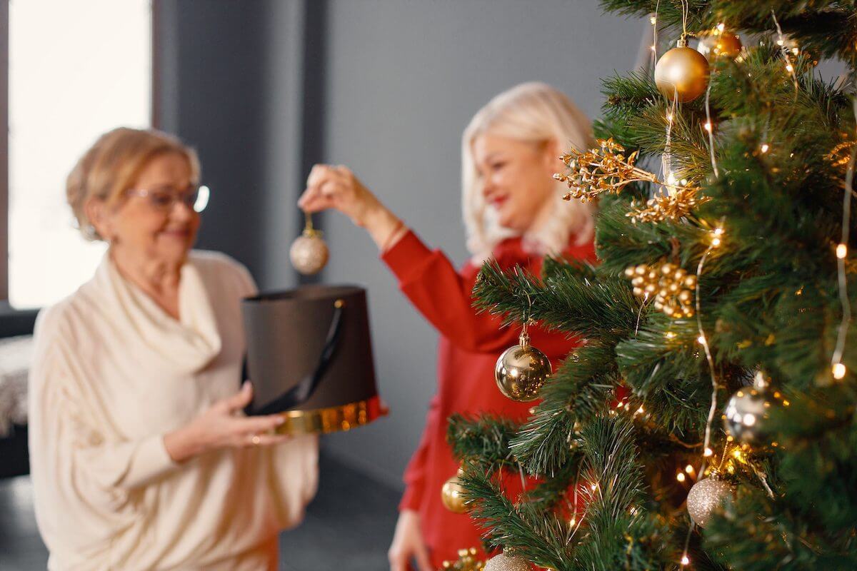 Senior Woman and Adult Daughter Decorate Christmas Tree SaraBella Senior Living