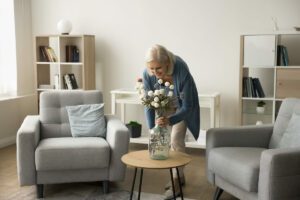 Picture of a happy older woman decorating her apartment with natural light.