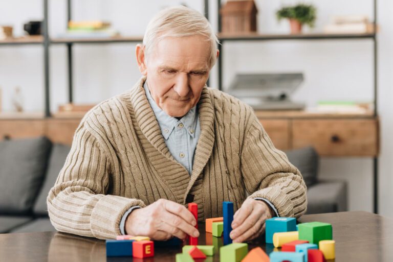 Older man playing with colorful shapes.