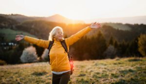 Older woman joyful at the top of the mountain.