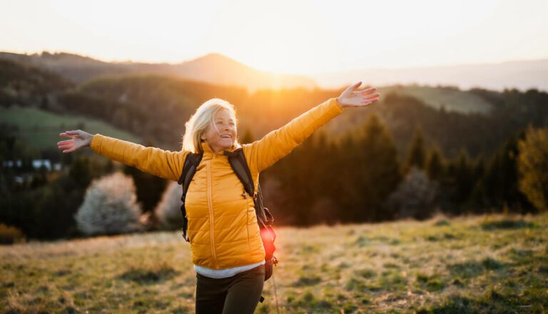 Older woman joyful at the top of the mountain.