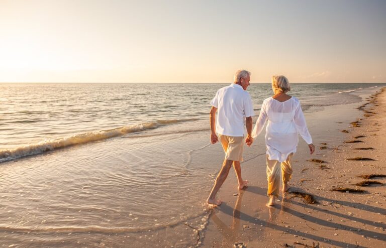 Couple of older adults walking down a beach