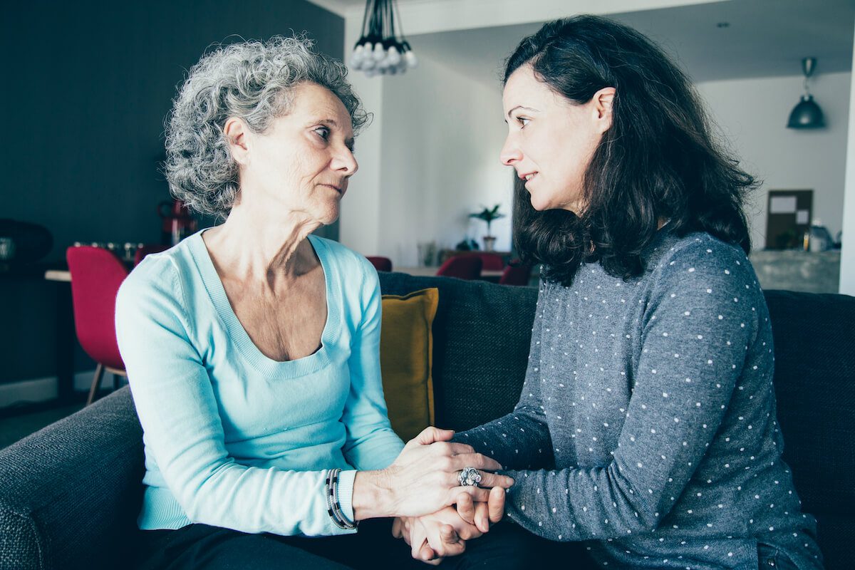 Family caregiver holding hands with an older woman